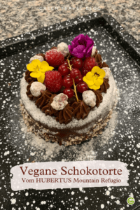 Pinterest Pin für die Vegane Schokotorte vom HUBERTUS MOuntainrefugio. Sie steht auf einnem schwarzen, mit Puderzucker bestäubten Untergrund.