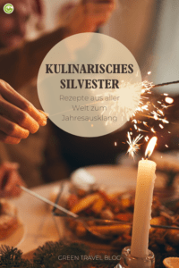 Eine Hand zündet eine Wunderkerze an einer Kerze an beim Silvesterdinner