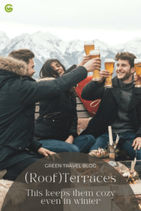 A group of young people are toasting with beer glasses and making happy faces. They are on the wintry terrace of the Rohrkopfhütte, which belongs to the hotel Das Rübezahl.