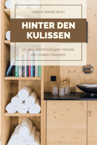 Zu sehen ist ein Regal mit sorgfältig gerollten Handtüchern in einem Hotelbadezimmer