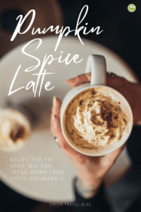A person holds a cup of pumpkin spice latte in their hands. 