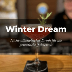 Ein roter alkoholfreier Cocktail, garniert mit Rosmarin, steht elegant auf einem Bartresen. Text-Overlays mit der Aufschrift „Winter Dream“ und „Get the recipe“. Gemütliche, einladende Atmosphäre.