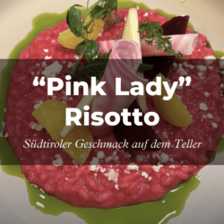 Ein leuchtend pinkes Risotto, garniert mit Kräutern, Zitrussegmenten und Käsestücken auf einem weißen Teller. Text-Overlays: „Pink Lady Risotto; Südtiroler Geschmack auf deinem Teller.“