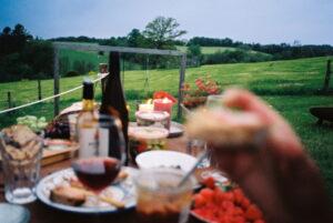 Picknicktisch mit Gläsern, Flaschen, Tellern und Schalen mit Essen vor einer grünen Landschaft im Bergischen Land