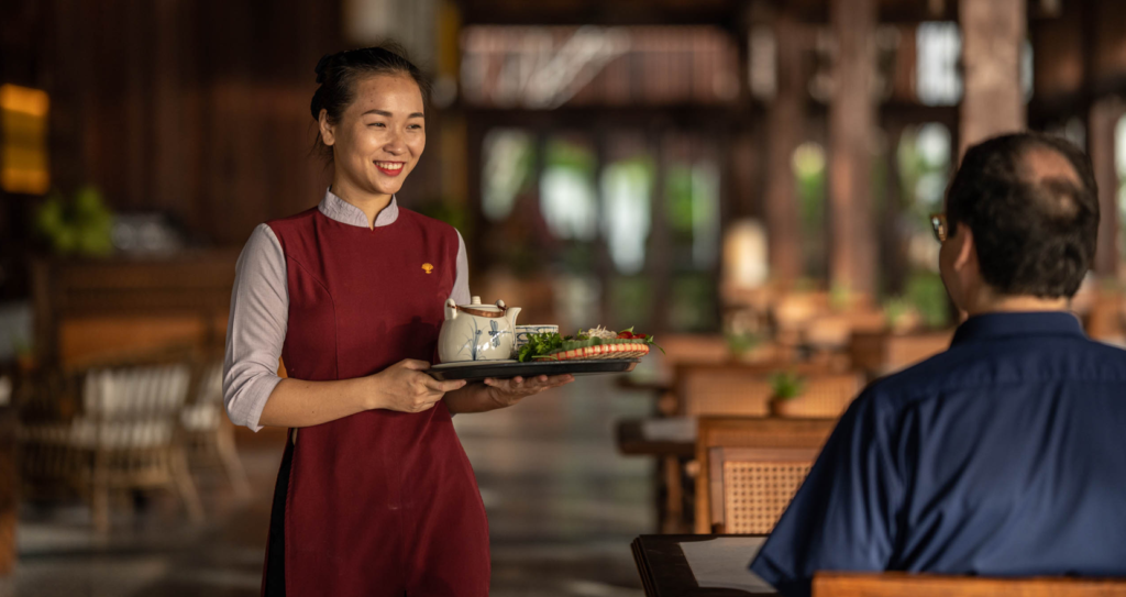 Freundliche Bedienung im vietnamesischen Hotel Restaurant bringt einen Teller mit Speisen