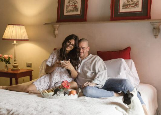 A couple and their dog on a hotel bed at the Relais del Maro