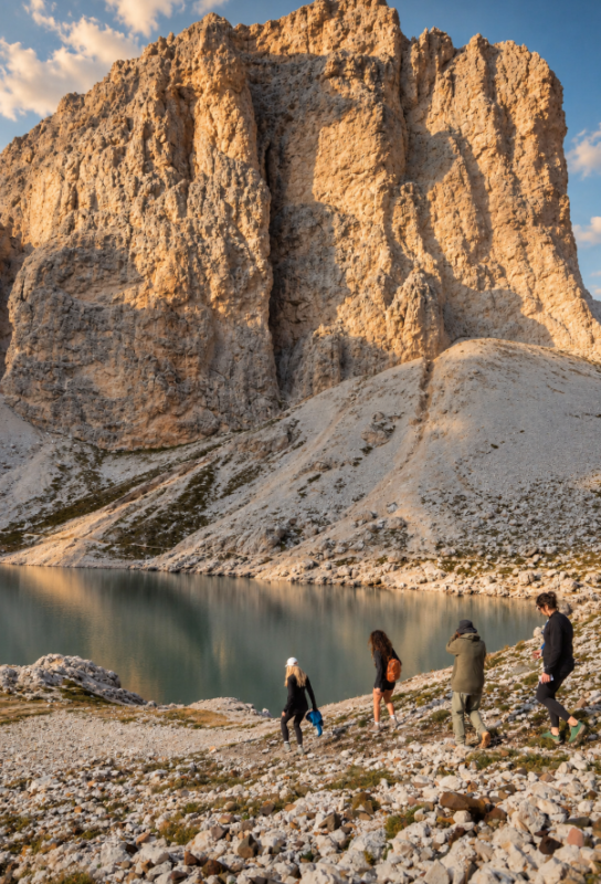 Hiking Guide Marnie Spögler wandert mit 3 Frauen durch die Dolomiten, das Gebirge wird in der Sonne angstrahlt.